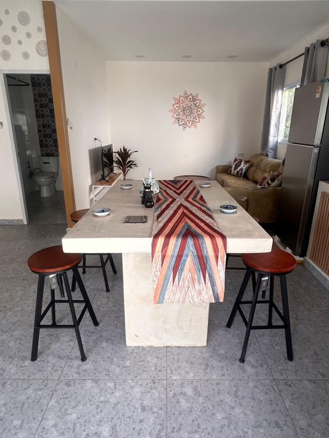 Concrete dining and work table with four stools, sofa behind